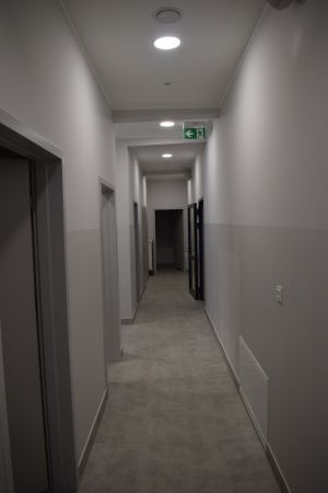 Długi, wąski korytarz z drzwiami po obu stronach