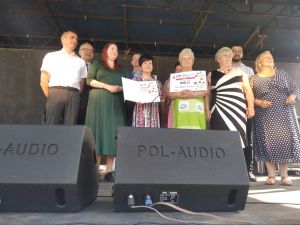 Grupka oficjeli, stojących na scenie i przemawiających do publiczności